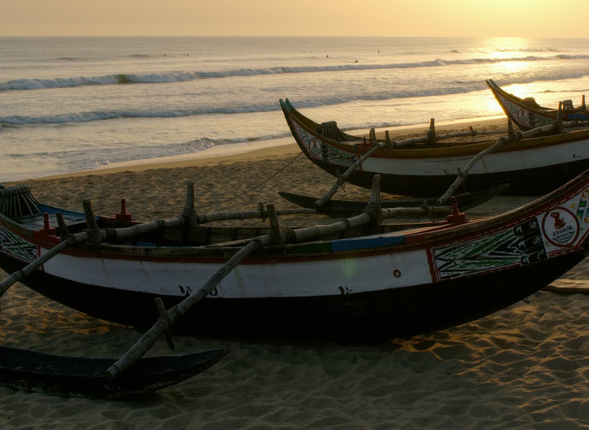 Pirogues colorées sur une plage de la Petite Côte au coucher du soleil