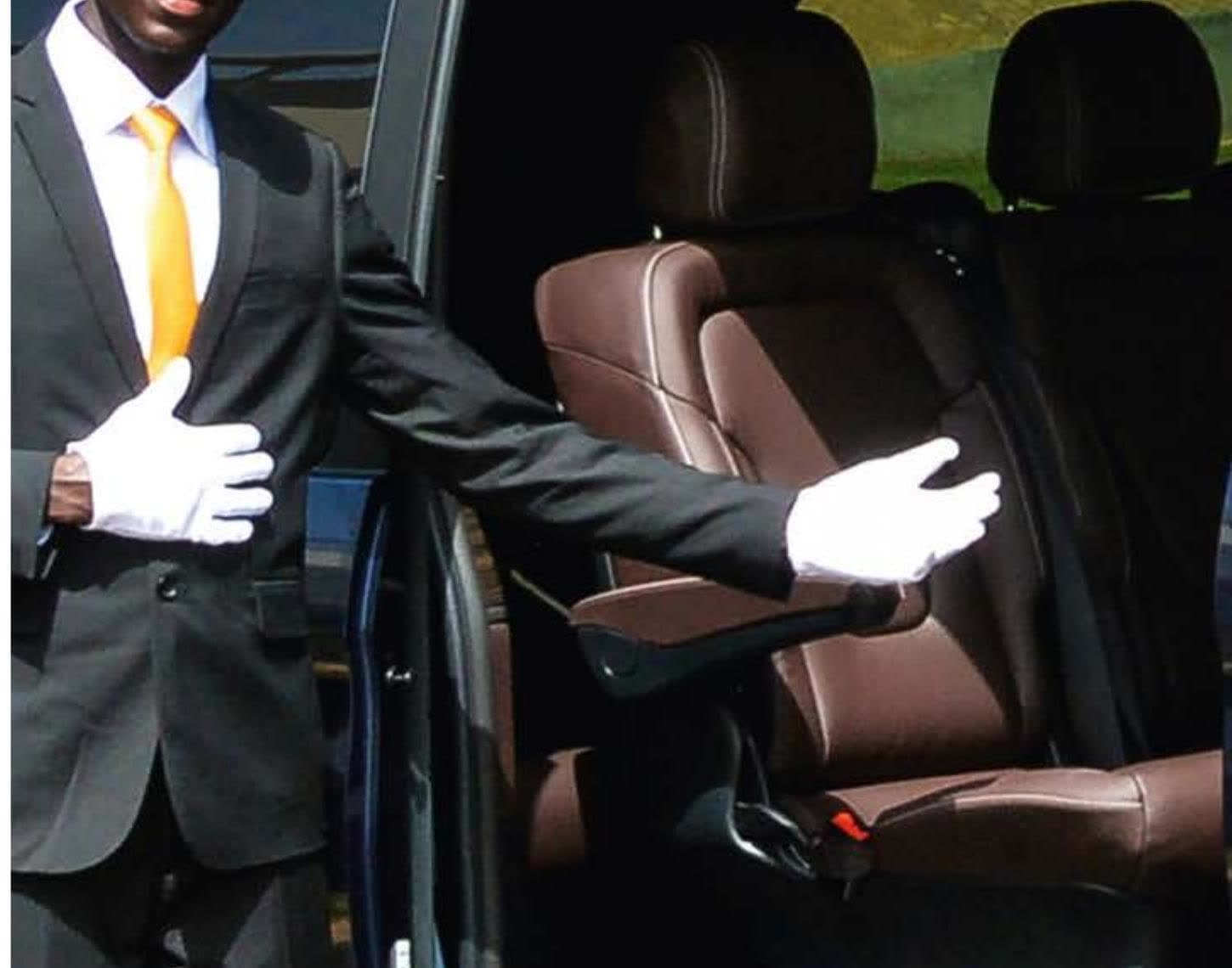 Chauffeur en gants blancs invitant à prendre place dans un van aux sièges de cuir