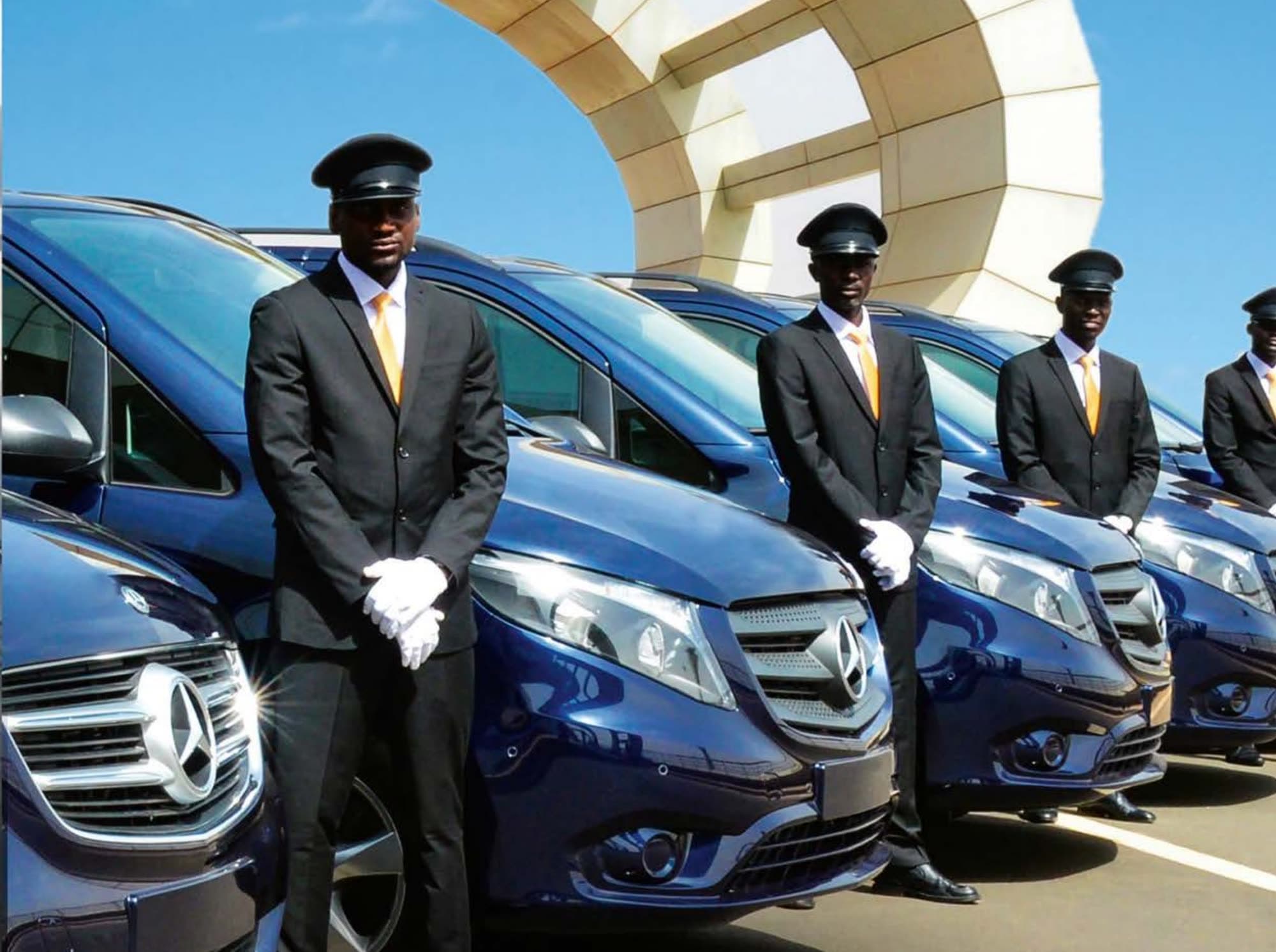 Chauffeurs en uniforme alignés devant des vans Mercedes bleu nuit